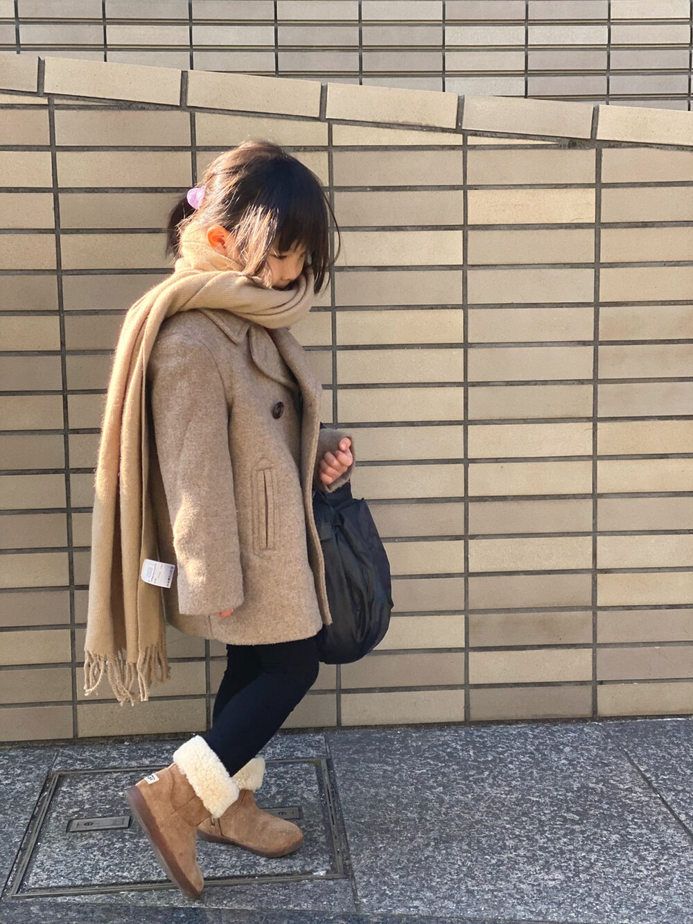 レッド系のスウェット、ベージュ系のピーコート、ブラック系のハンドバッグを着用したキッズの冬コーディネートの2枚目の写真