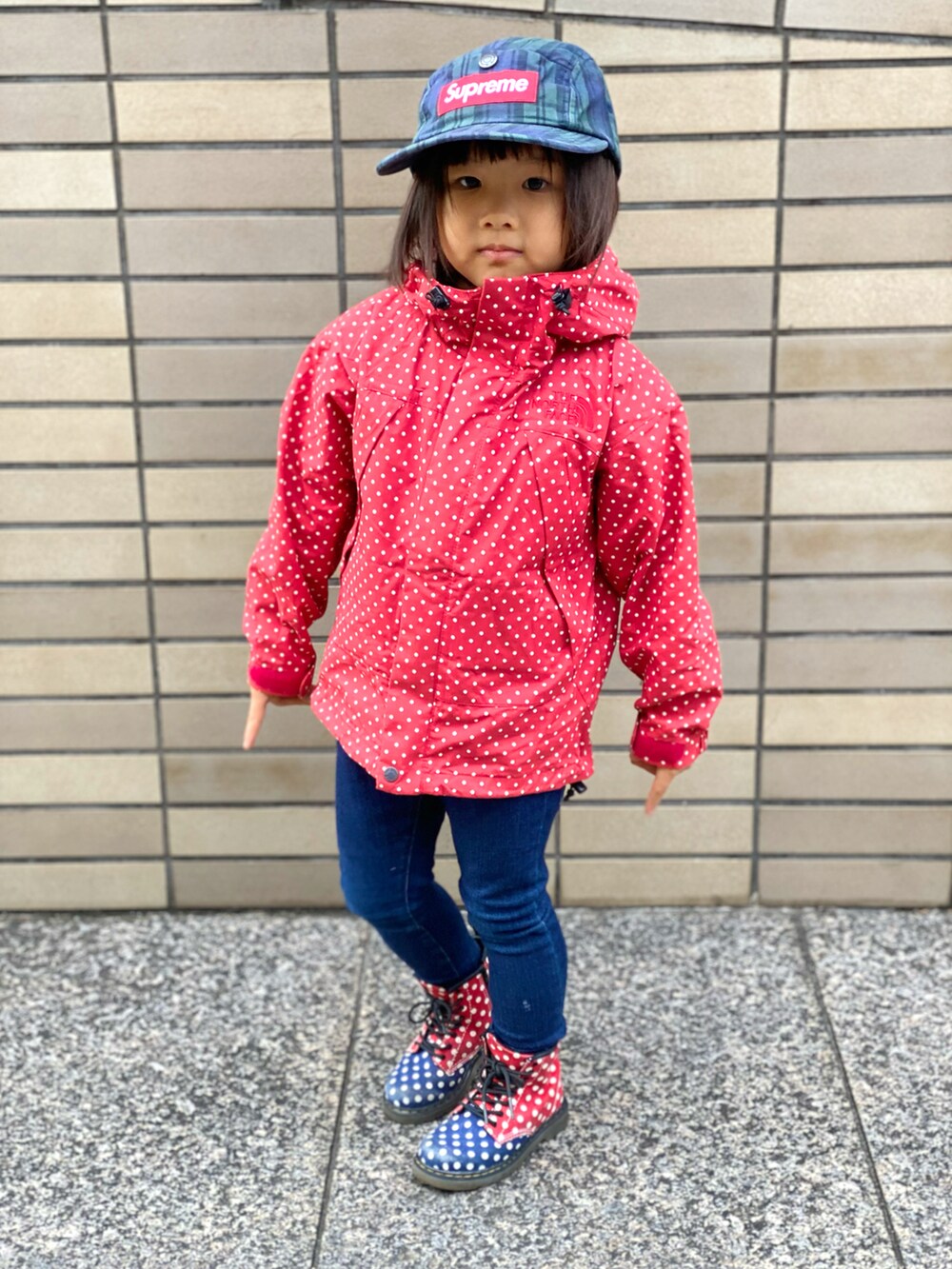 レッド系のナイロンジャケット、その他のブーツ、ブルー系のデニムパンツを着用したキッズの秋コーディネートの3枚目の写真