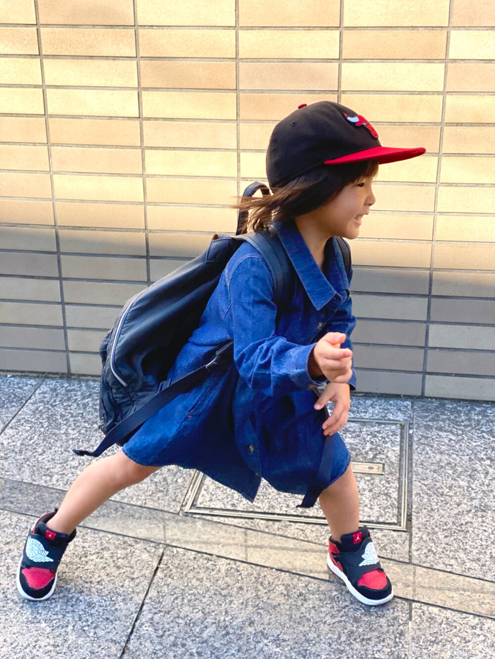 ブルー系のワンピース、ベージュ系のトップス、ブラック系のスニーカーを着用したキッズの秋コーディネートの3枚目の写真