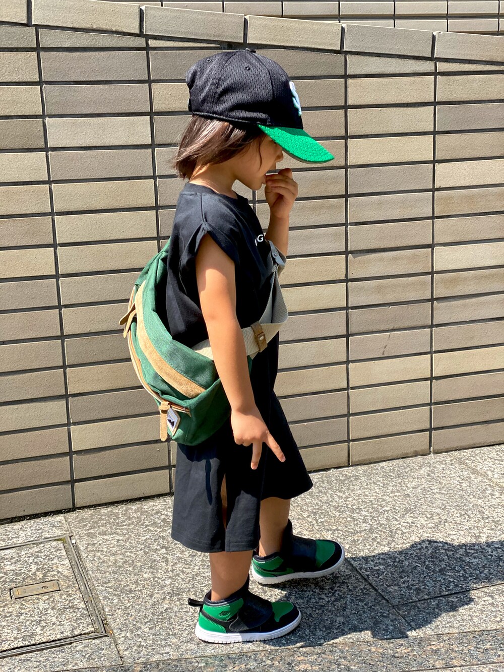ブラック系のワンピース、グリーン系のボディバッグ/ウエストポーチ、グリーン系のスニーカーを着用したキッズの秋コーディネートの2枚目の写真