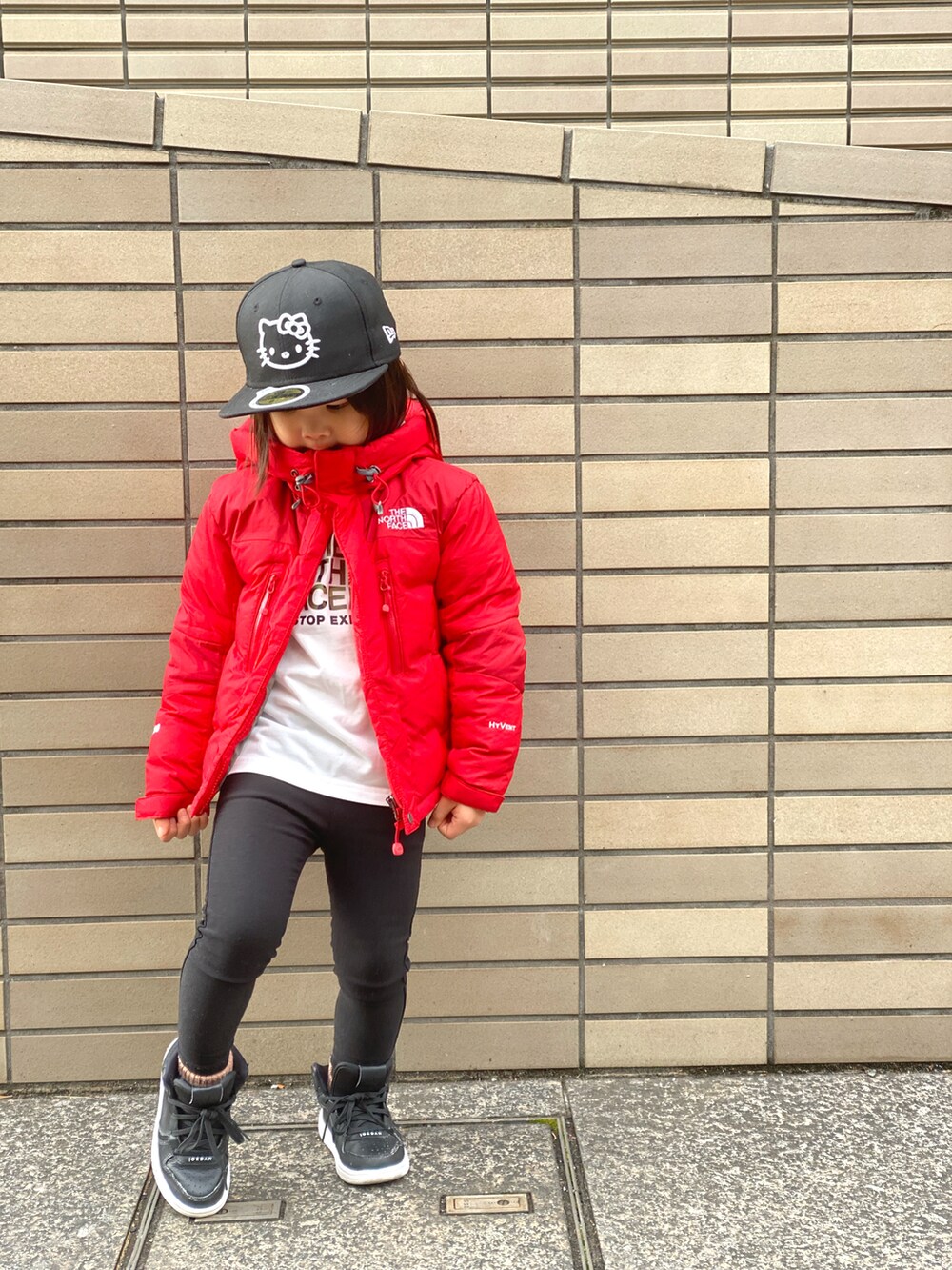 レッド系のダウンジャケット/コート、ホワイト系のTシャツ/カットソー、ブラック系のその他パンツを着用したキッズの冬コーディネートの2枚目の写真