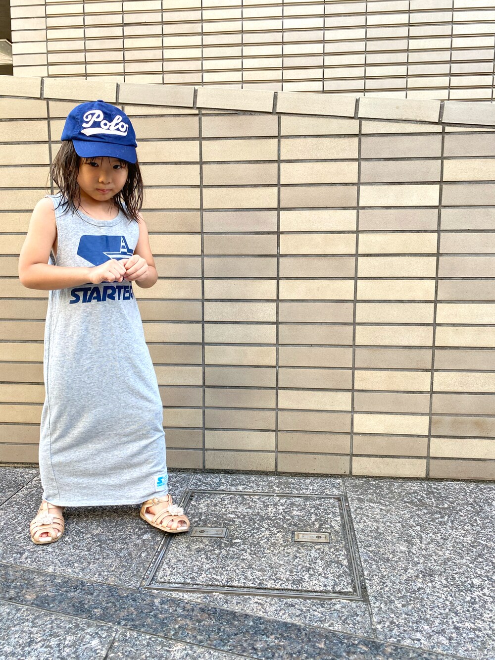 グレー系のワンピース、ブルー系のキャップを着用したキッズの夏コーディネートの2枚目の写真