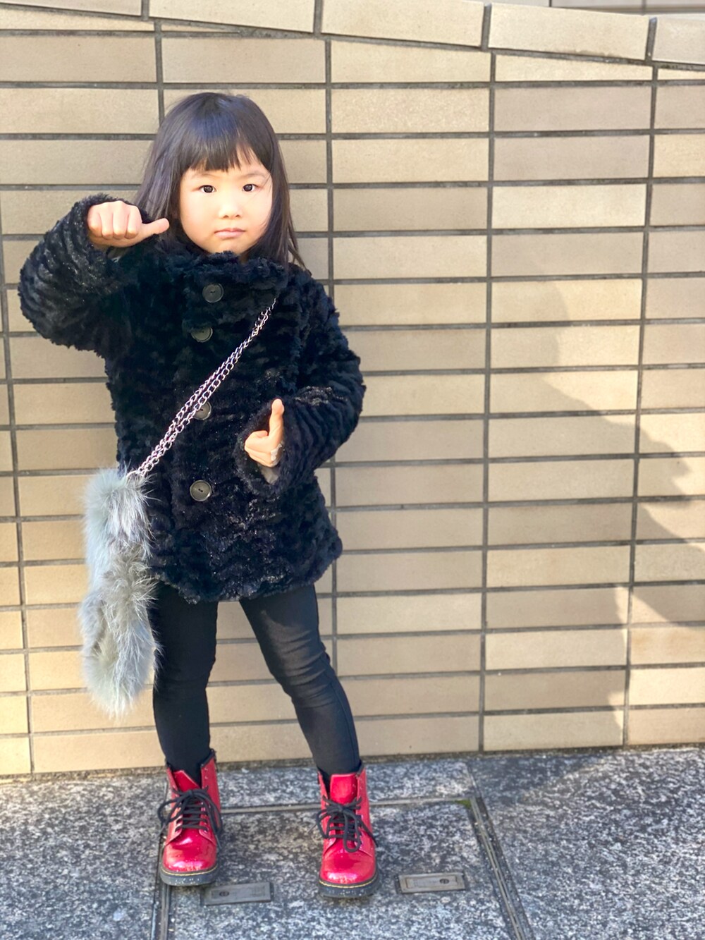 「キッズファッション、patagonia、Dr.Martens、ブーツ、コート、黒コーデ、赤、シンプルコーデ、ショルダーバッグ、カジュアルコーデ、ファーバッグ、ワントーンコーデ」｜「patagoniaのアイテム（ジャケット/アウター、ブラック系）」を使った、Rin&Rayさん（キッズ・100cm）の冬コーディネートの2枚目の写真