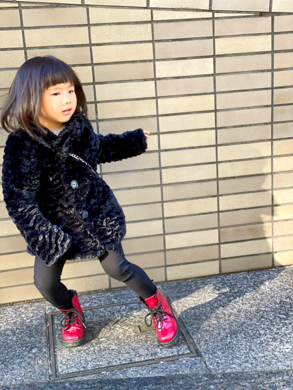 「キッズファッション、patagonia、Dr.Martens、ブーツ、コート、黒コーデ、赤、シンプルコーデ、ショルダーバッグ、カジュアルコーデ、ファーバッグ、ワントーンコーデ」｜「patagoniaのアイテム（ジャケット/アウター、ブラック系）」を使った、Rin&Rayさん（キッズ・100cm）の冬コーディネートの3枚目の写真