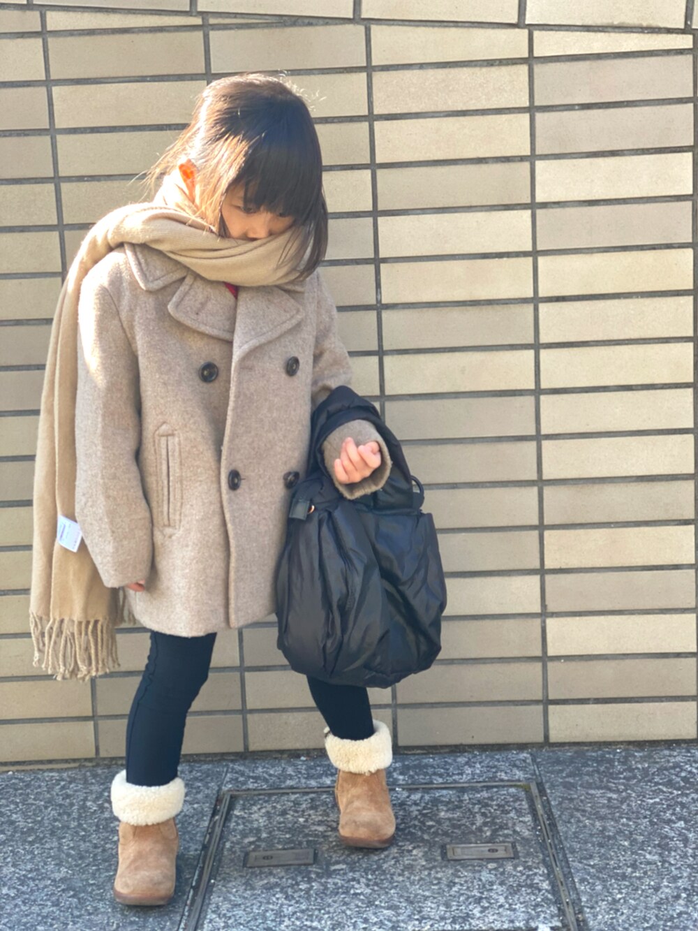 レッド系のスウェット、ベージュ系のピーコート、ブラック系のハンドバッグを着用したキッズの冬コーディネートの4枚目の写真