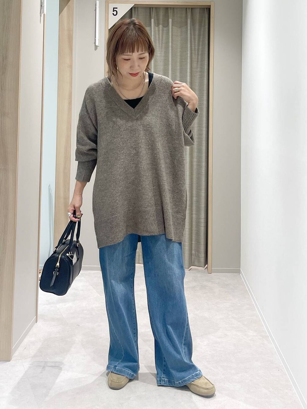 ブルー系のチェスターコート、ブラウン系のニット/セーター、ブラック系のボストンバッグを着用したレディースの秋コーディネートの5枚目の写真