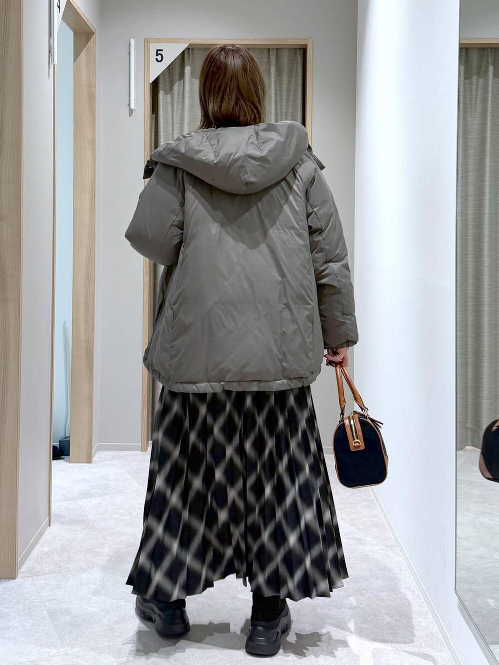 ブラウン系のダウンジャケット/コート、ブラック系のニット/セーター、ブラック系のブーツを着用したレディースの冬コーディネートの3枚目の写真