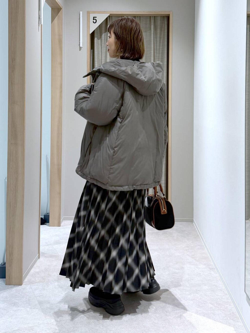 ブラウン系のダウンジャケット/コート、ブラック系のニット/セーター、ブラック系のブーツを着用したレディースの冬コーディネートの2枚目の写真