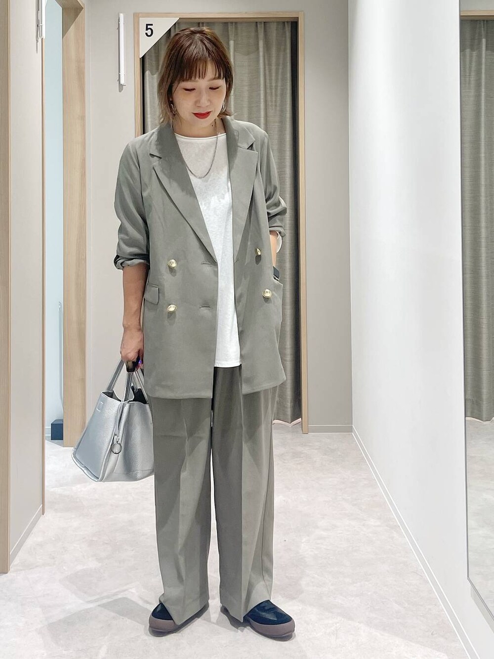 ブラック系のスニーカー、ベージュ系のテーラードジャケット、ベージュ系のスラックスを着用したレディースの秋コーディネートの2枚目の写真