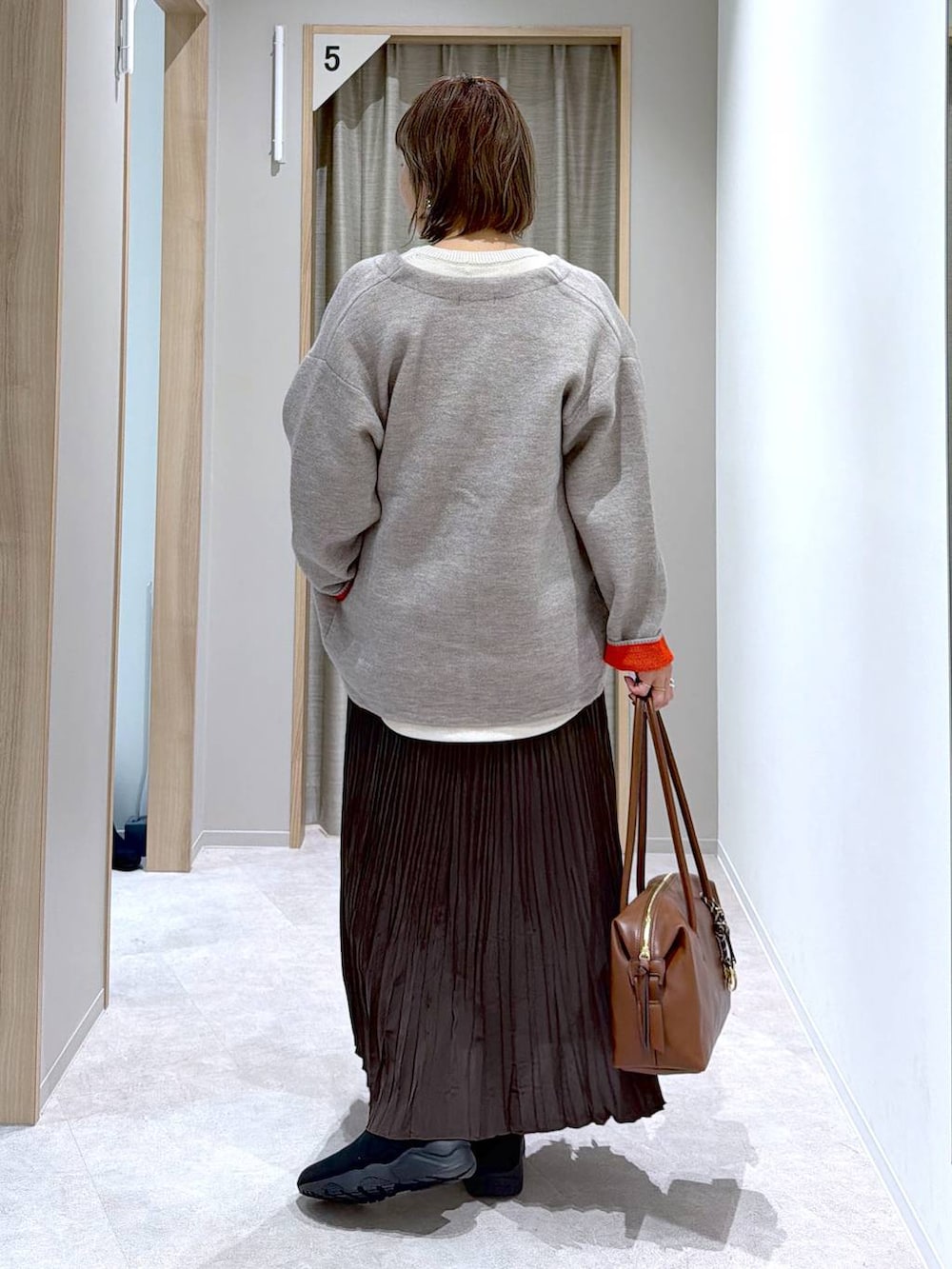 ベージュ系のニット/セーター、ブラウン系のボストンバッグ、ブラック系のブーツを着用したレディースの冬コーディネートの3枚目の写真