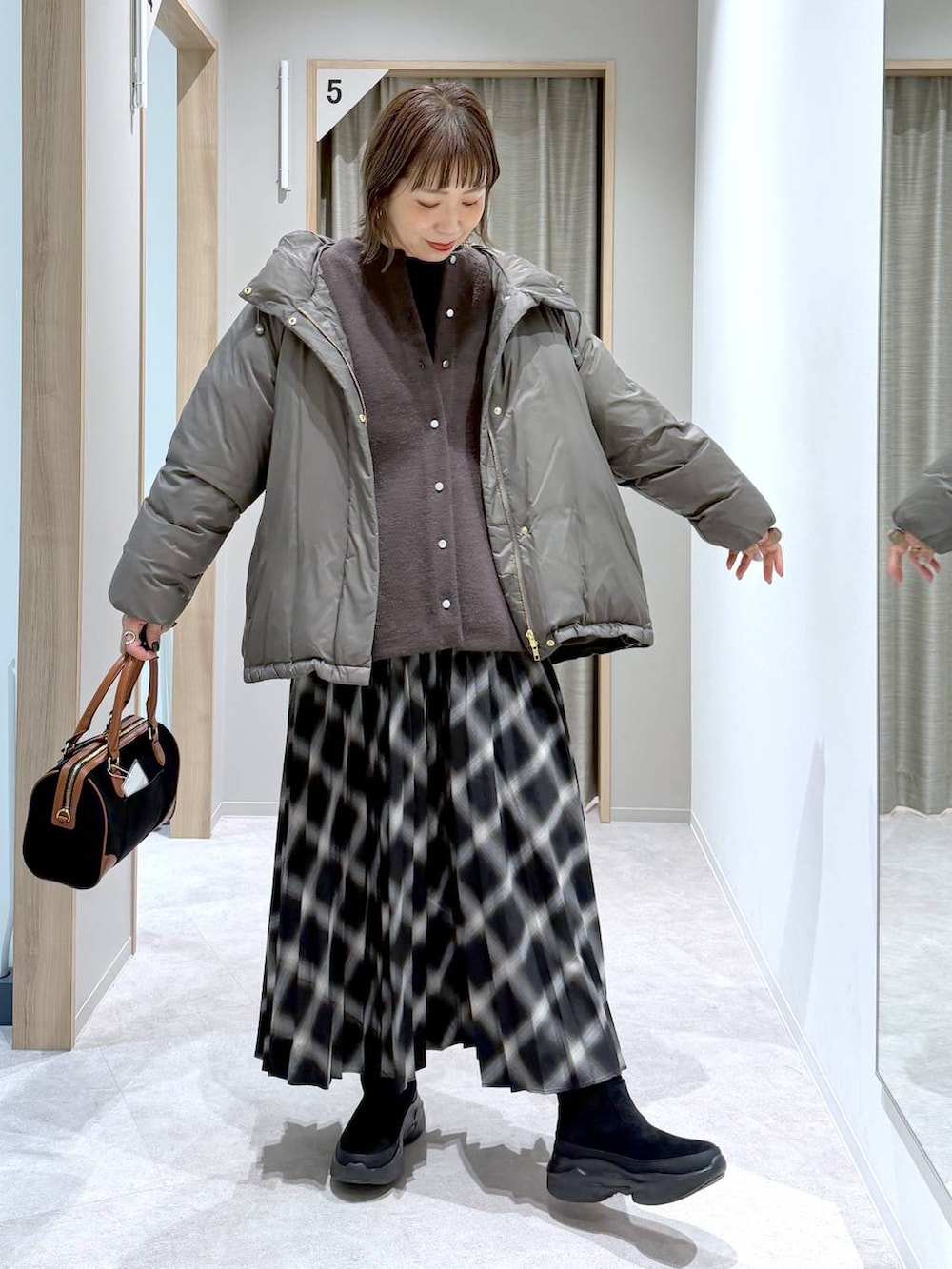 ブラウン系のダウンジャケット/コート、ブラック系のニット/セーター、ブラック系のブーツを着用したレディースの冬コーディネートの4枚目の写真