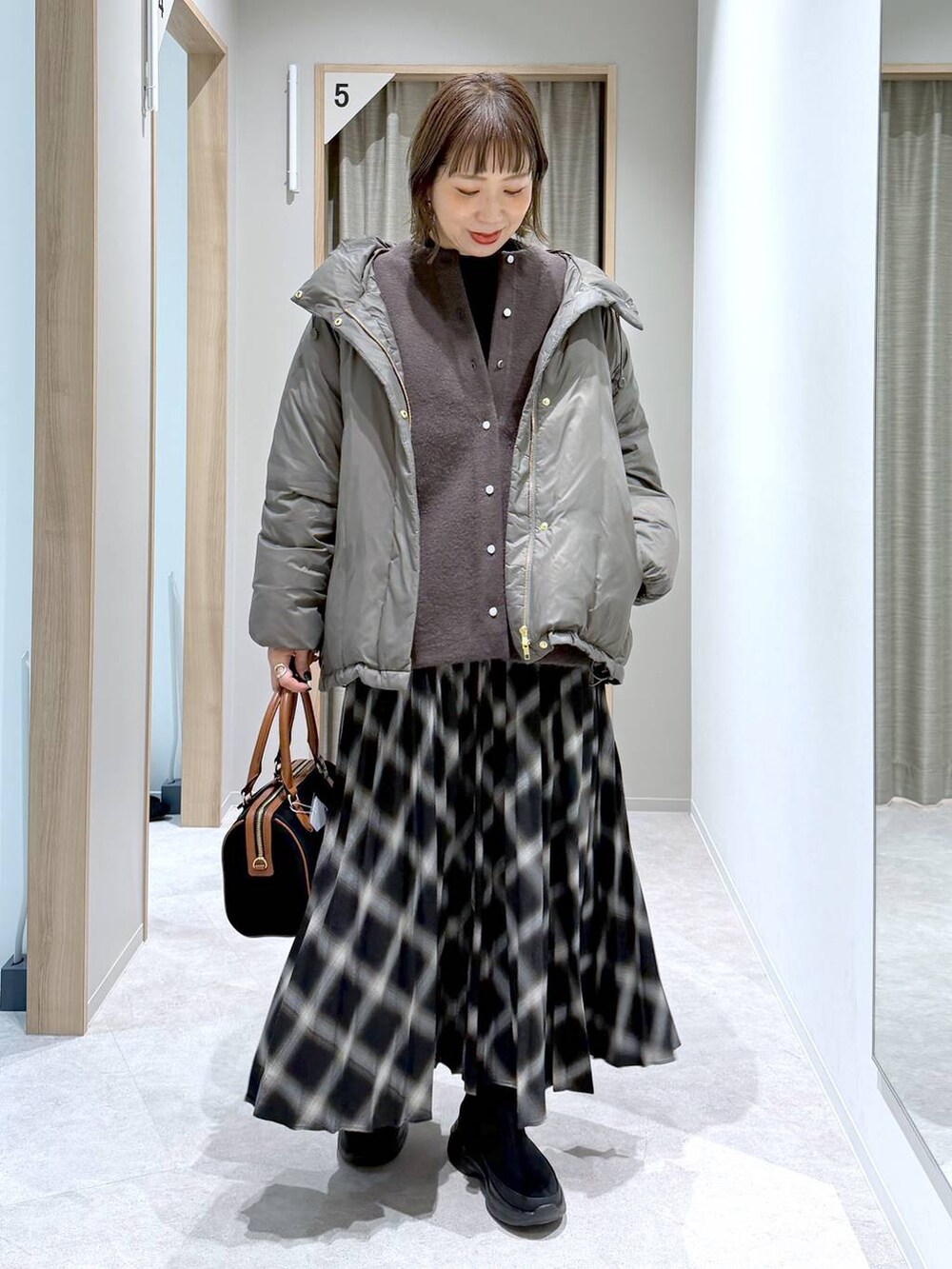 ブラウン系のダウンジャケット/コート、ブラック系のニット/セーター、ブラック系のブーツを着用したレディースの冬コーディネートの5枚目の写真