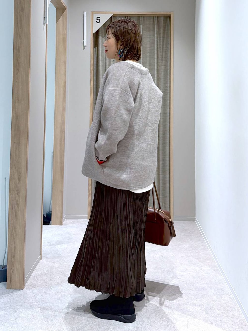 ベージュ系のニット/セーター、ブラウン系のボストンバッグ、ブラック系のブーツを着用したレディースの冬コーディネートの2枚目の写真