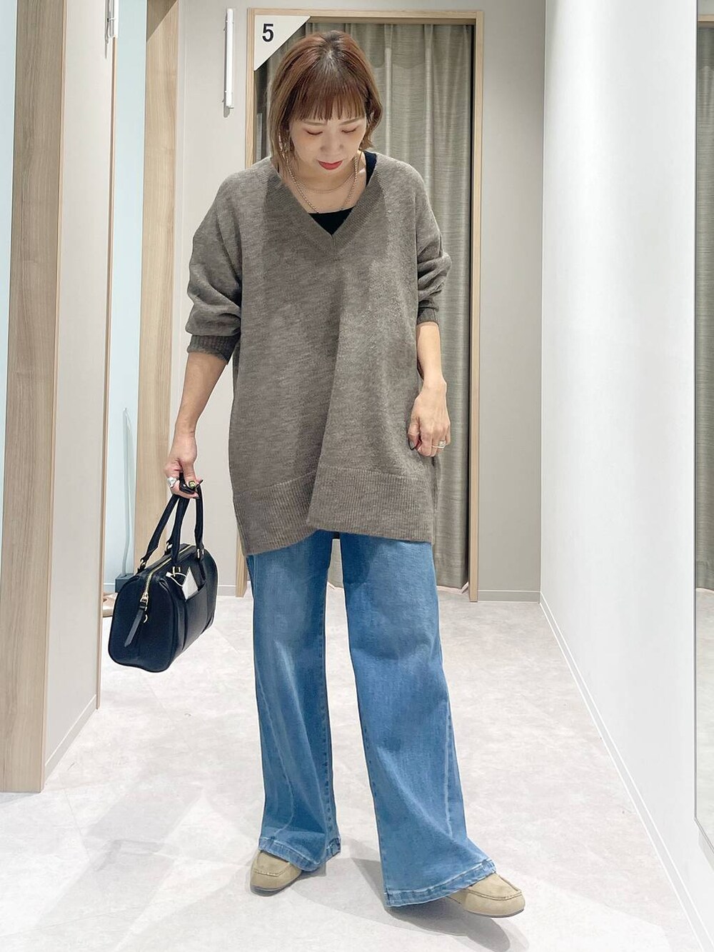 ブルー系のチェスターコート、ブラウン系のニット/セーター、ブラック系のボストンバッグを着用したレディースの秋コーディネートの7枚目の写真