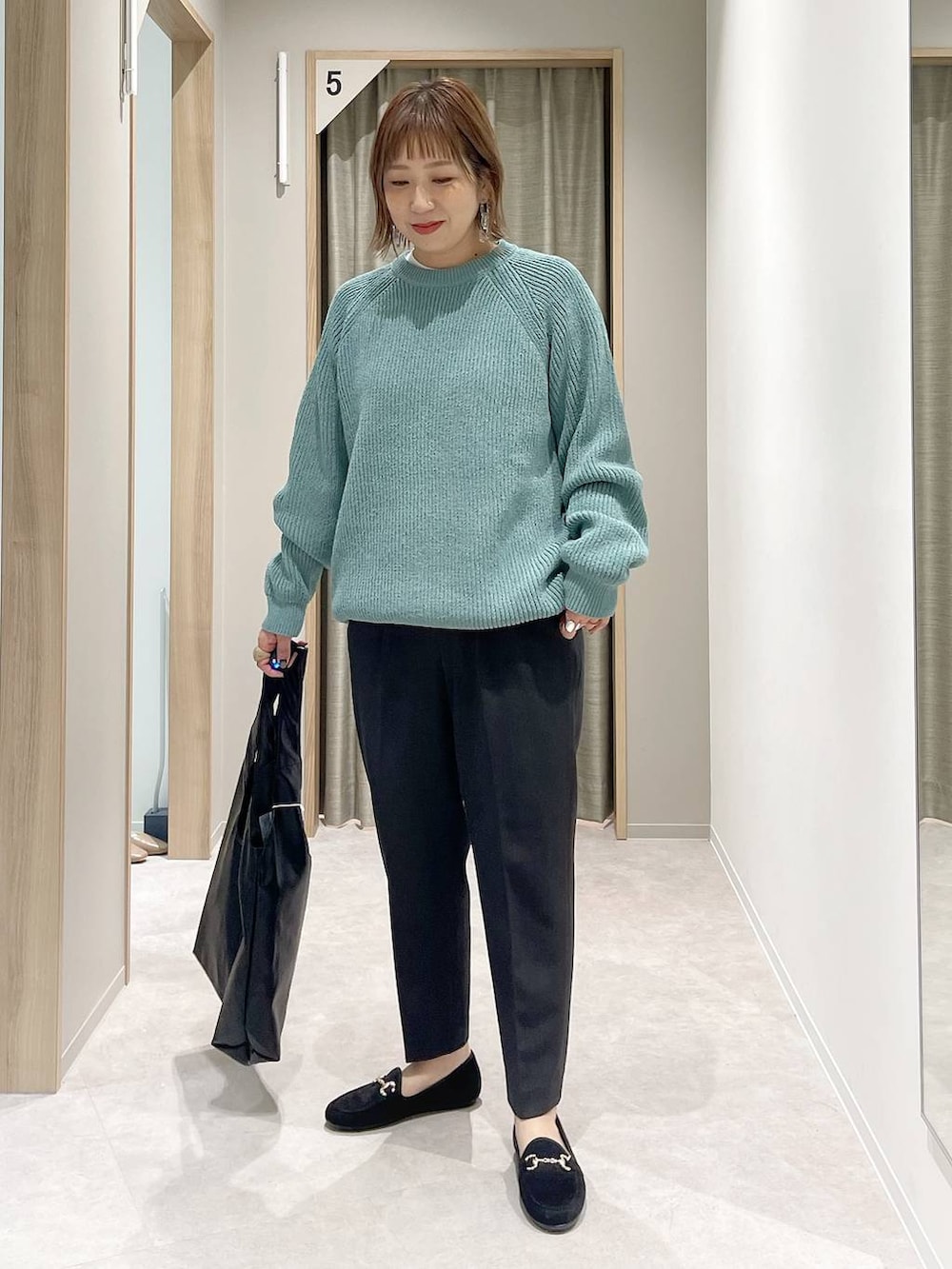 グレー系のその他パンツ、ホワイト系のTシャツ/カットソー、グリーン系のニット/セーターを着用したレディースの秋コーディネートの3枚目の写真