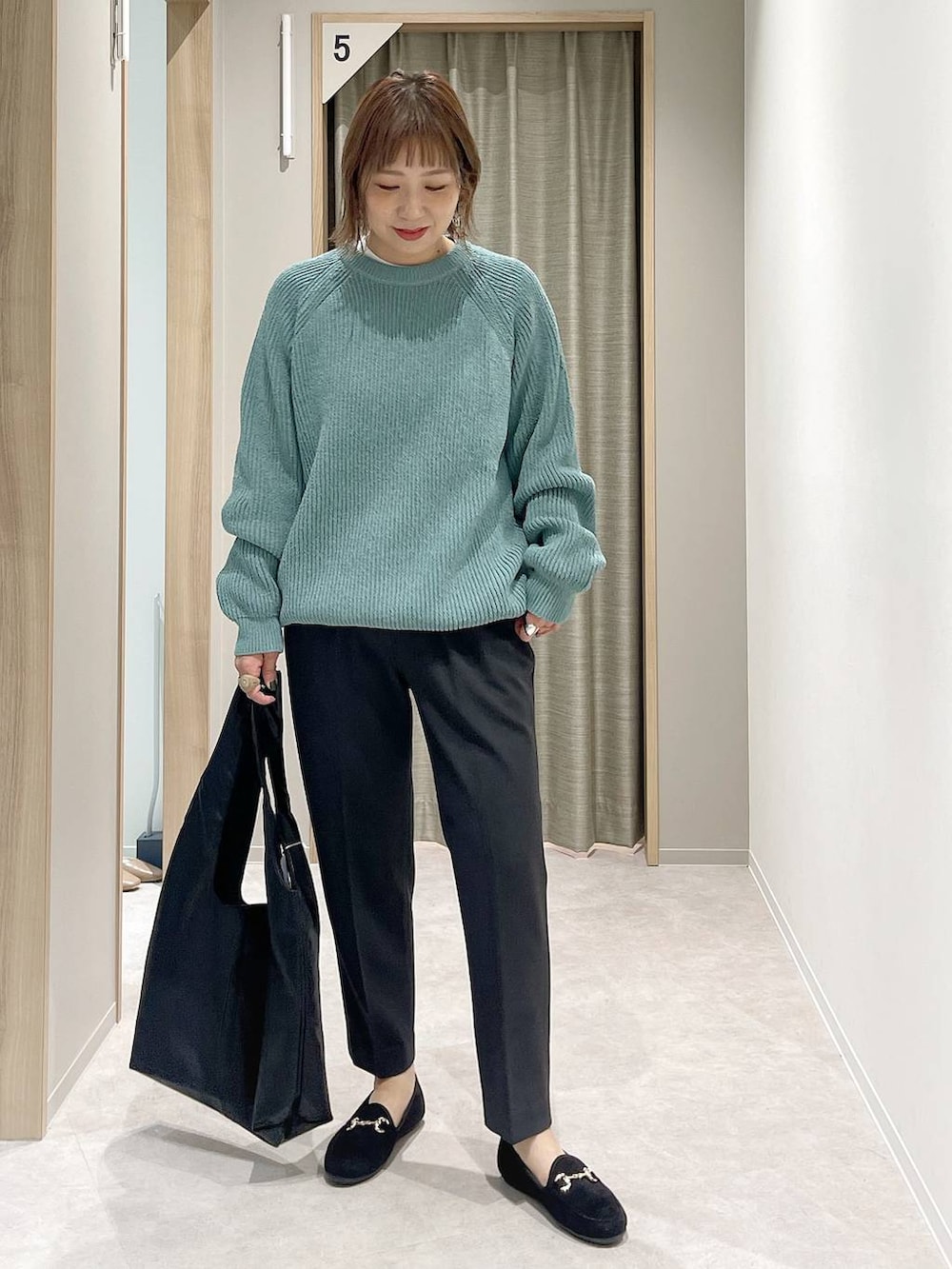 グレー系のその他パンツ、ホワイト系のTシャツ/カットソー、グリーン系のニット/セーターを着用したレディースの秋コーディネートの4枚目の写真