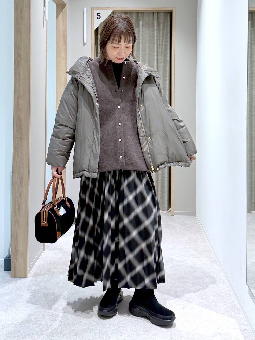 ブラウン系のダウンジャケット/コート、ブラック系のニット/セーター、ブラック系のブーツを着用したレディースの冬コーディネートの6枚目の写真