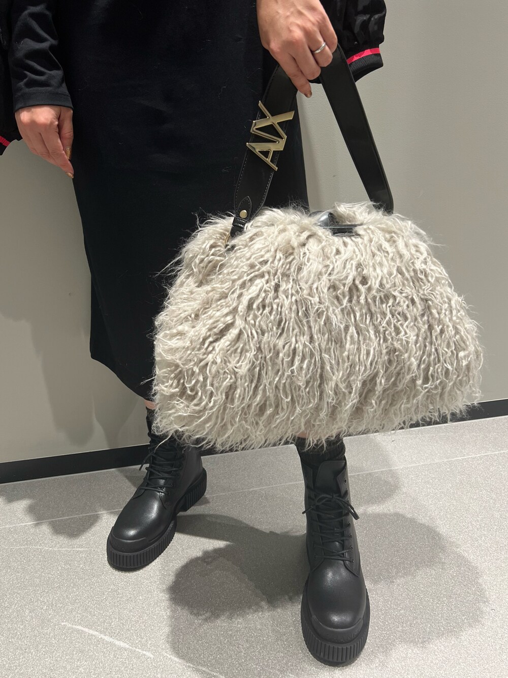 ブラック系のブルゾン、ブラック系のワンピース、ベージュ系のハンドバッグを着用したレディースの秋コーディネートの3枚目の写真