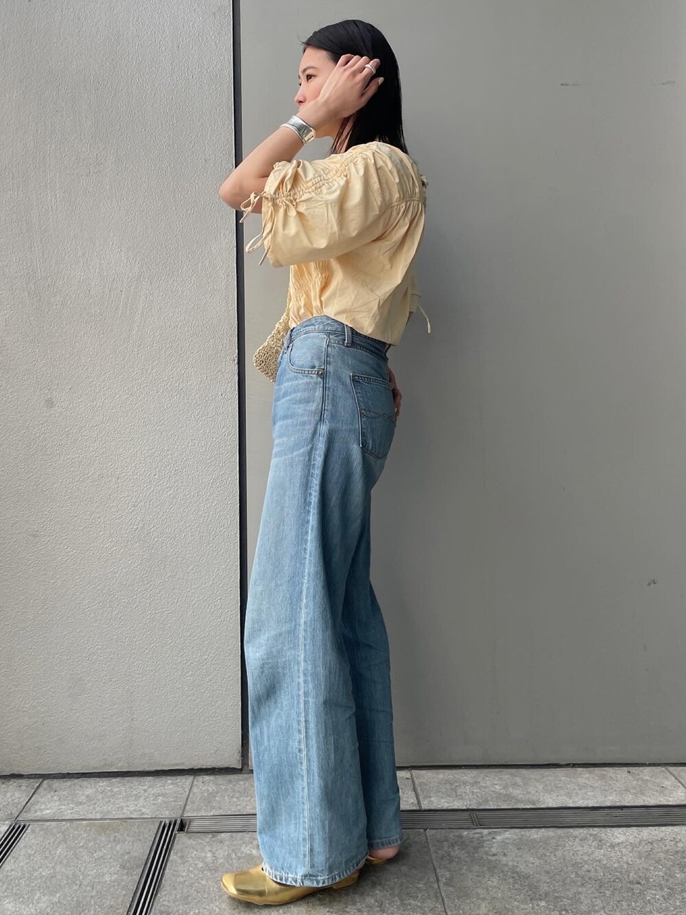 ブルー系のデニムパンツ、イエロー系のシャツ/ブラウス、ベージュ系のショルダーバッグを着用したレディースの春コーディネートの2枚目の写真