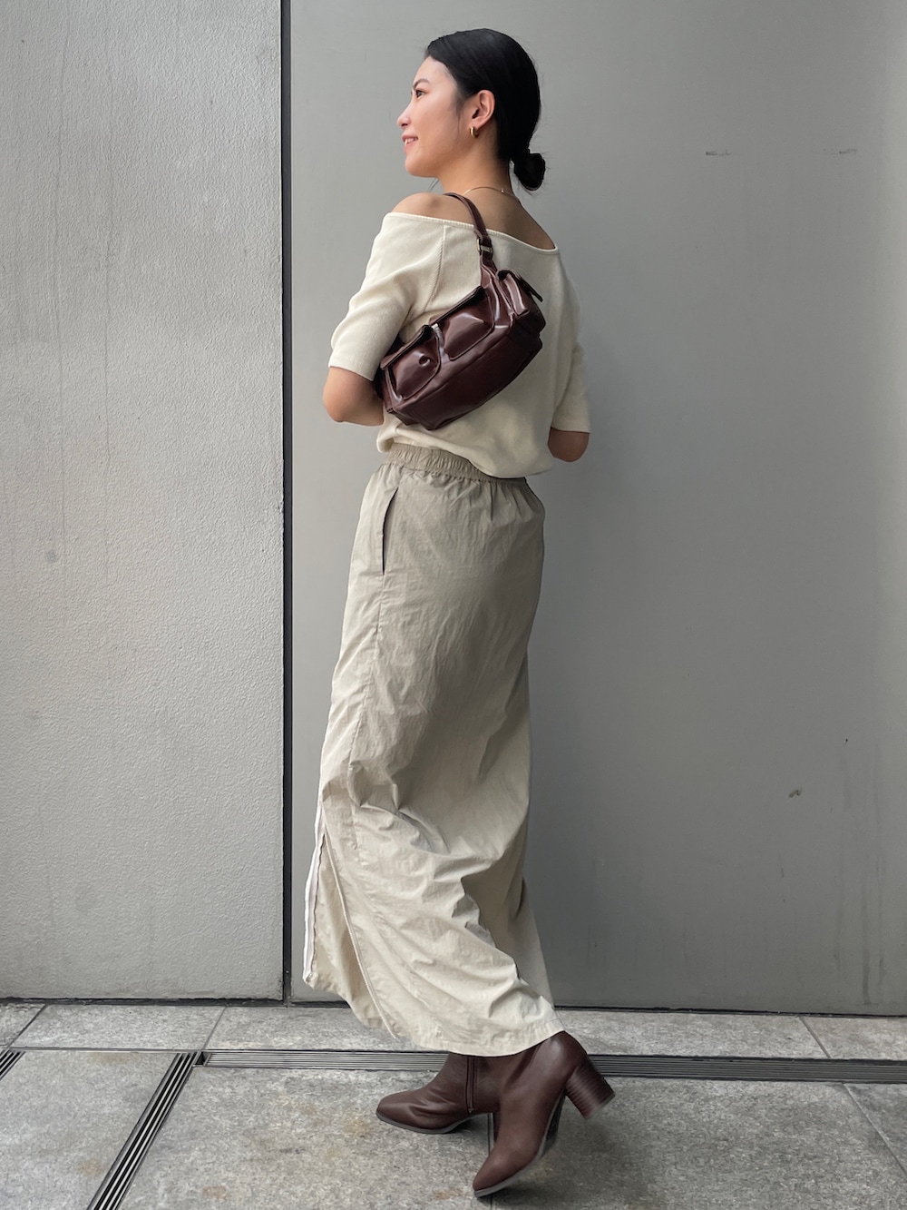 ベージュ系のスカート、ホワイト系のTシャツ/カットソー、ブラウン系のブーツを着用したレディースの夏コーディネートの4枚目の写真