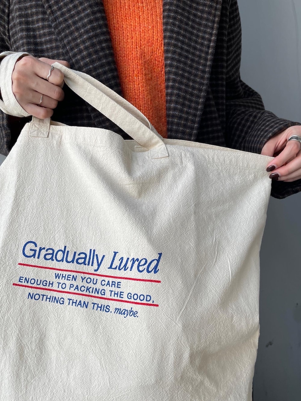 オレンジ系のニット/セーター、その他のチェスターコート、ブルー系のデニムパンツを着用したレディースの冬コーディネートの2枚目の写真