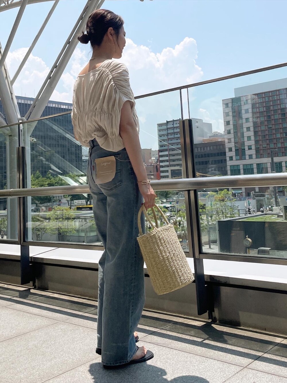 ホワイト系のシャツ/ブラウス、ブルー系のデニムパンツ、ベージュ系のかごバッグを着用したレディースの夏コーディネートの3枚目の写真