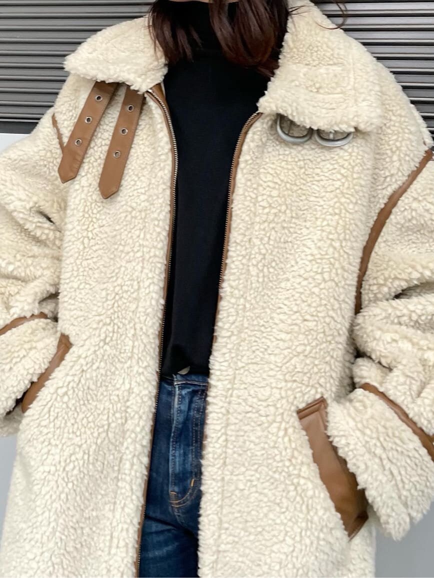 ブラック系のニット/セーター、ホワイト系のムートンコート、ブルー系のデニムパンツを着用したレディースの冬コーディネートの2枚目の写真