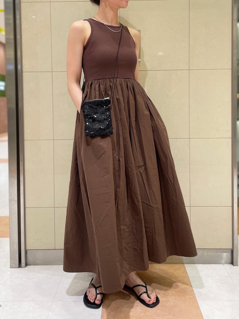 ブラウン系のワンピース、ブラック系のショルダーバッグ、ブラック系のサンダルを着用したレディースの春コーディネートの2枚目の写真