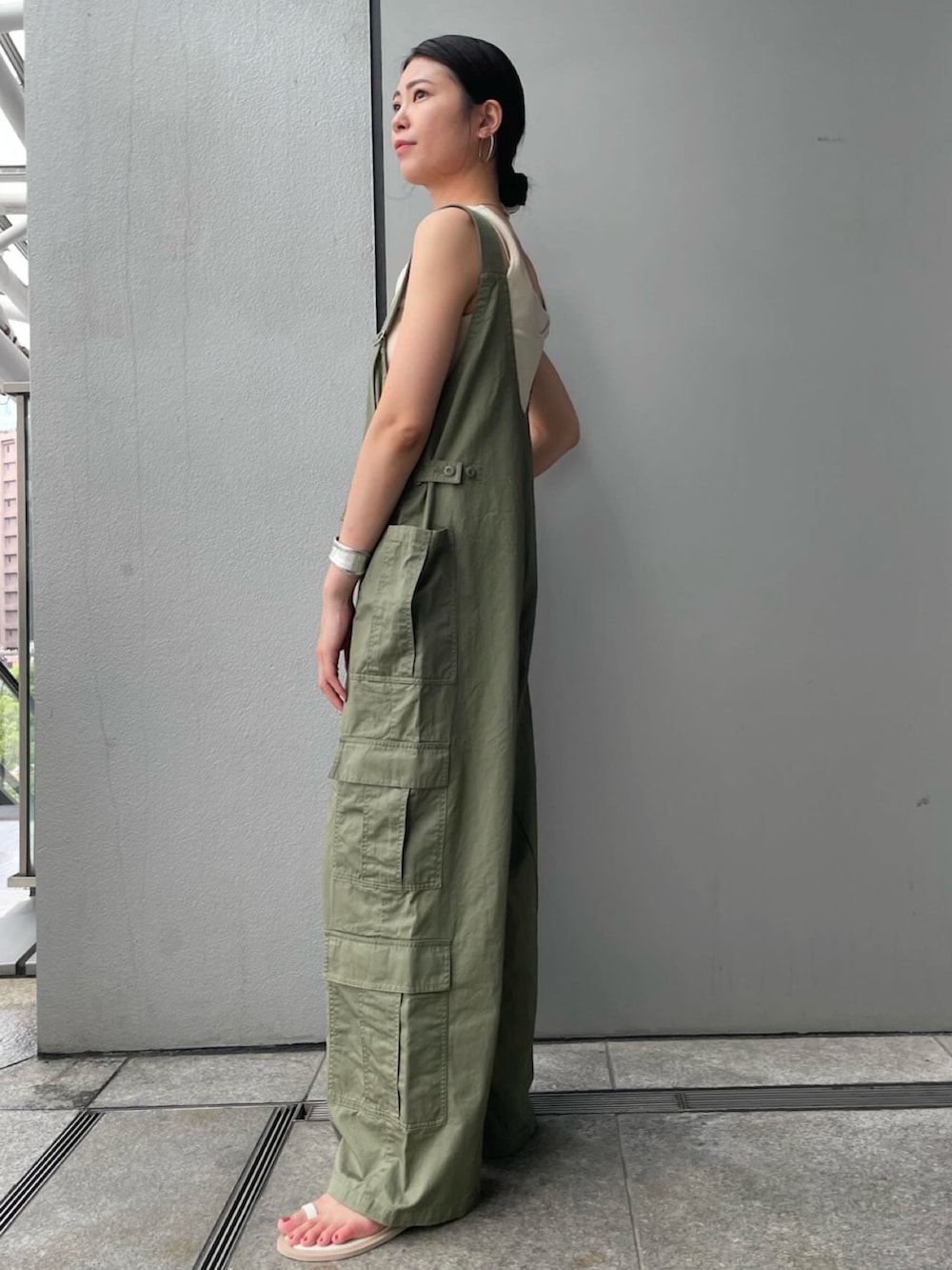 グリーン系のサロペット/オーバーオール、ブラウン系のベスト、ホワイト系のキャミソールを着用したレディースの夏コーディネートの2枚目の写真