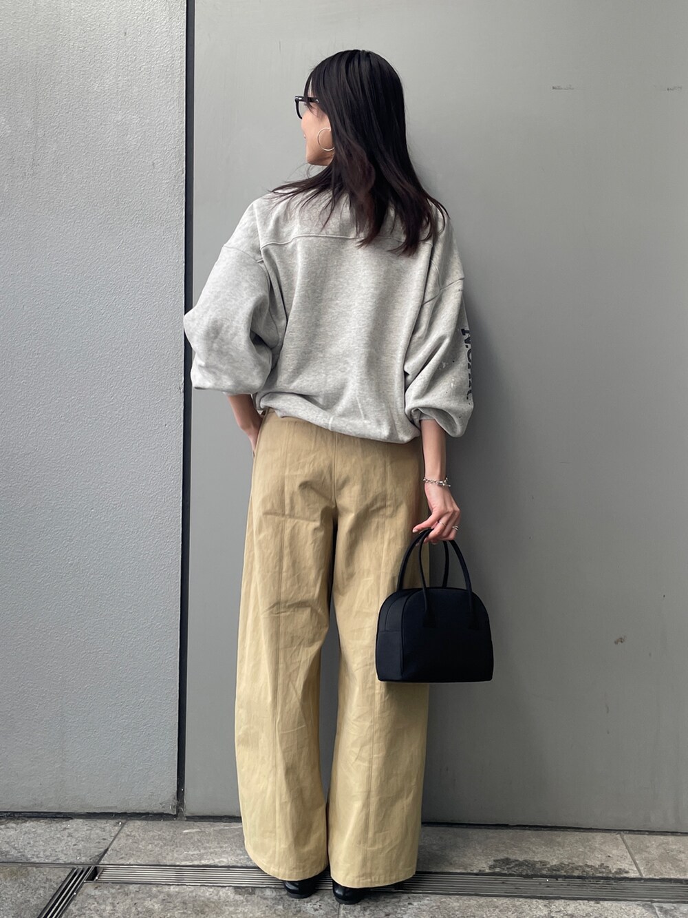 グレー系のスウェット、ベージュ系のチノパンツ、ブラック系のボストンバッグを着用したレディースの冬コーディネートの3枚目の写真