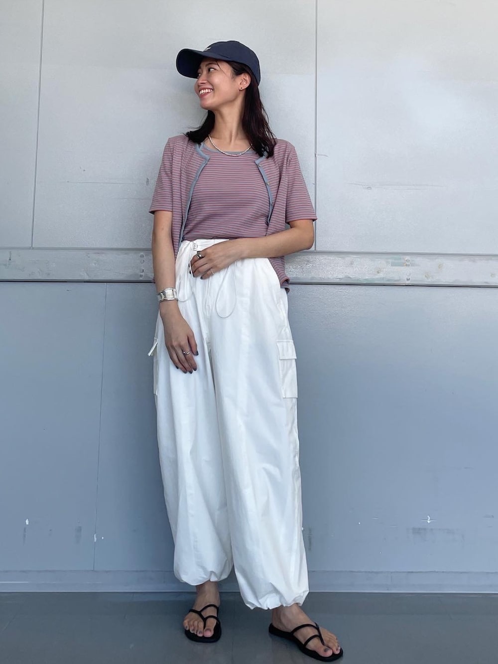 ホワイト系のその他パンツ、オレンジ系のキャミソール、ブルー系のキャップを着用したレディースの夏コーディネートの2枚目の写真