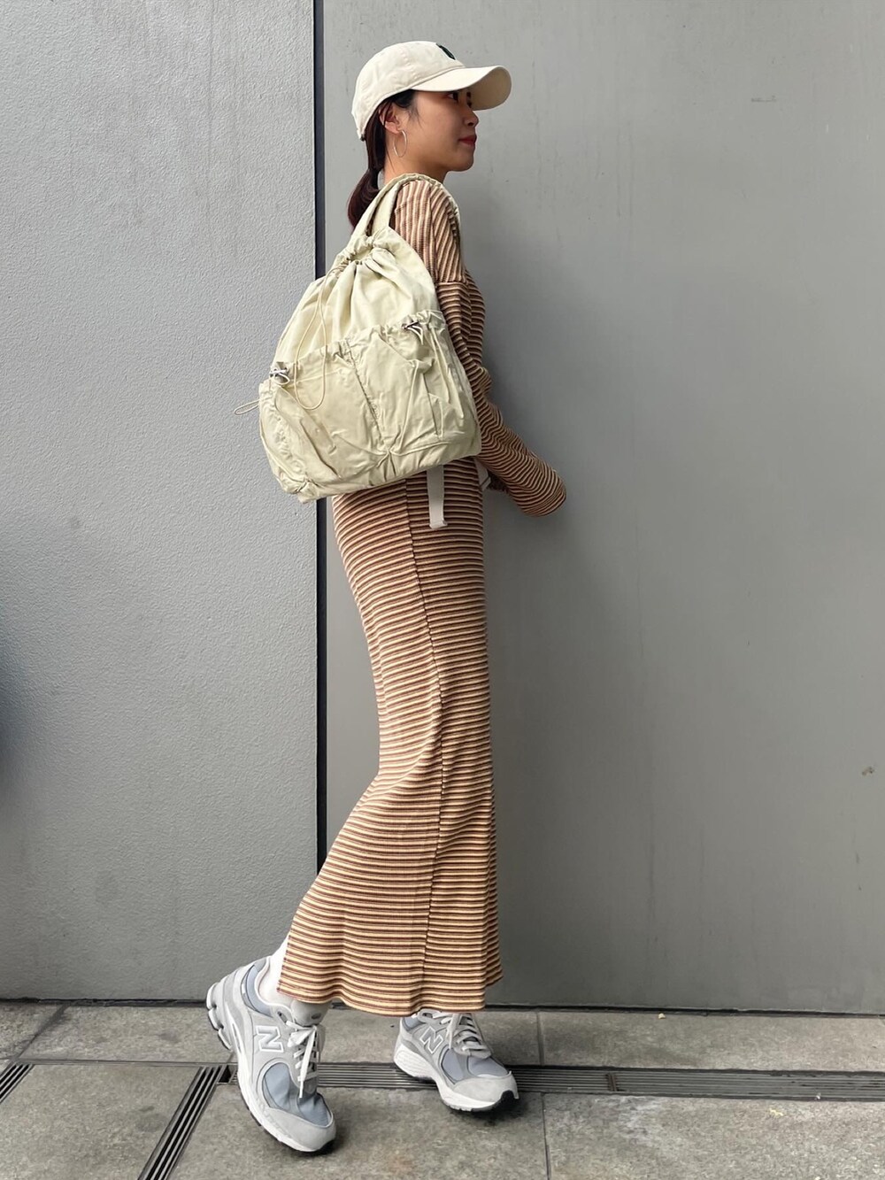 イエロー系のワンピース、ブルー系のデニムジャケット、ベージュ系のバックパック/リュックを着用したレディースの冬コーディネートの2枚目の写真