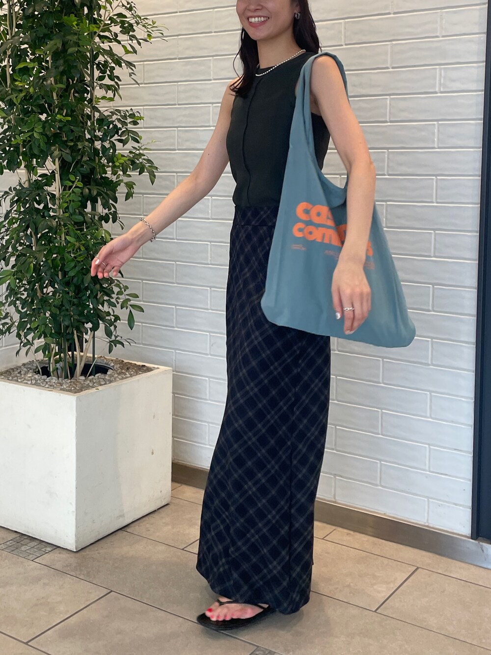 ブルー系のスカート、グレー系のタンクトップ、ブルー系のトートバッグを着用したレディースの夏コーディネートの2枚目の写真