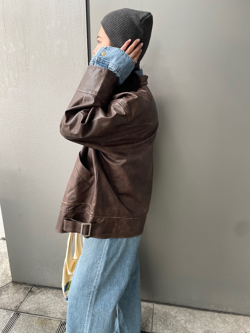 ブラウン系のブルゾン、ホワイト系のエコバッグ/サブバッグ、ブルー系のデニムパンツを着用したレディースの冬コーディネートの4枚目の写真