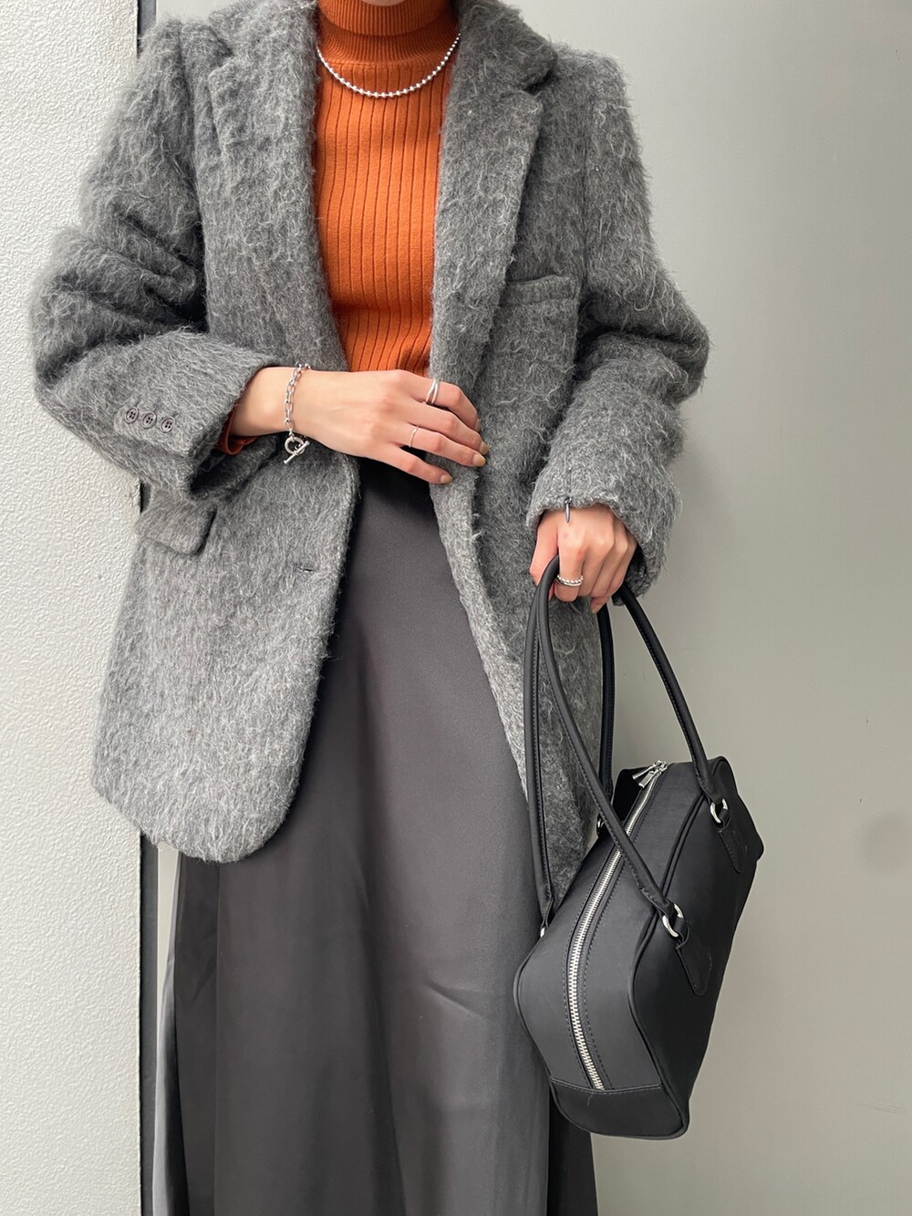 グレー系のテーラードジャケット、ブラック系のスカート、ブラック系のハンドバッグを着用したレディースの冬コーディネートの4枚目の写真