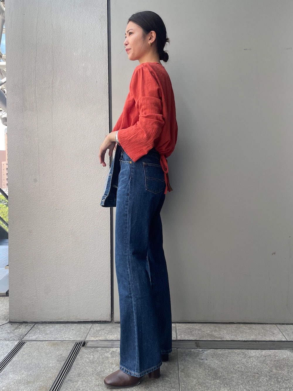 ブルー系のデニムパンツ、オレンジ系のシャツ/ブラウス、ブルー系のデニムジャケットを着用したレディースの夏コーディネートの2枚目の写真