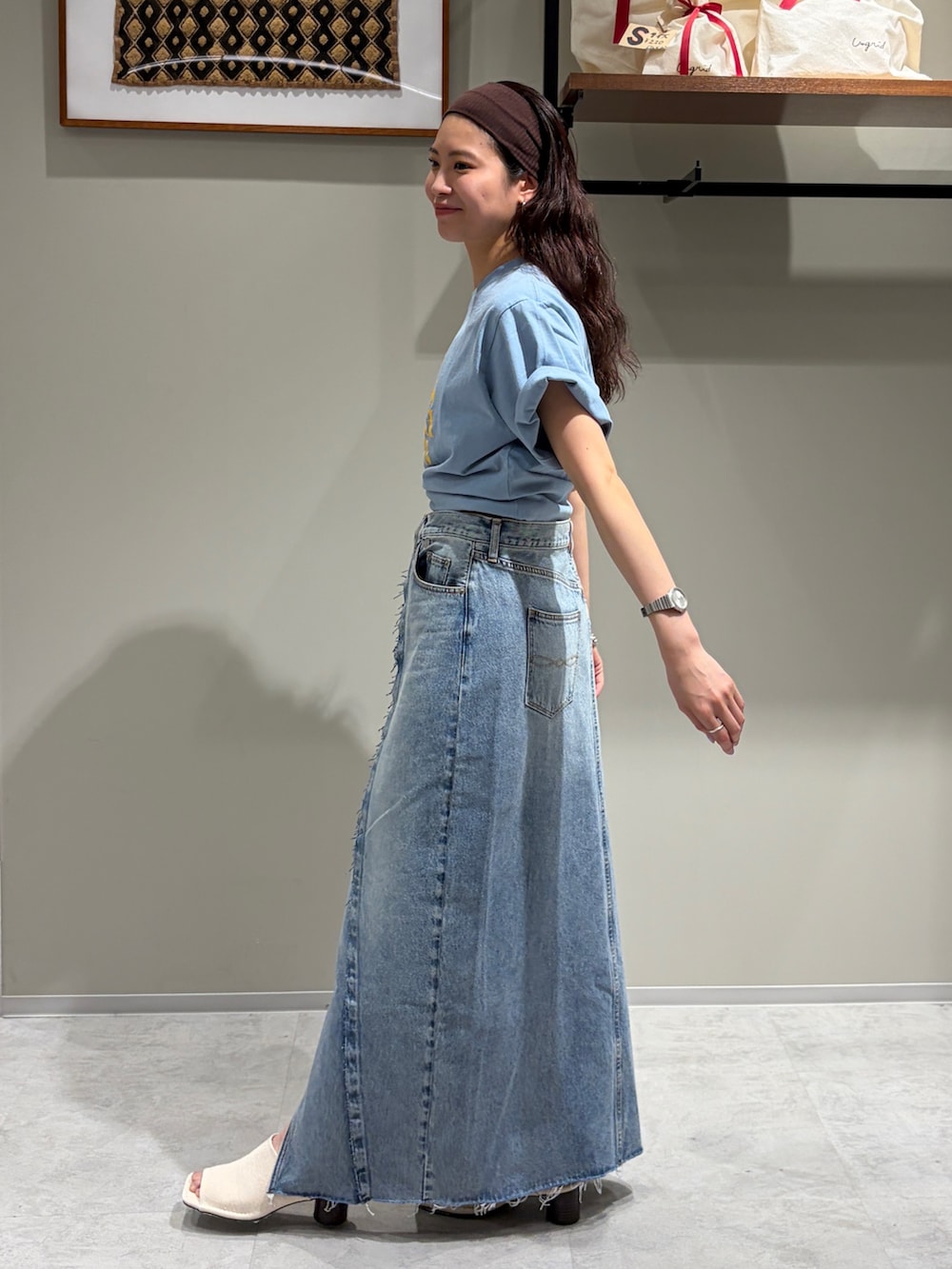 ブルー系のデニムスカート、ブルー系のTシャツ/カットソー、ホワイト系のサンダルを着用したレディースの春コーディネートの2枚目の写真