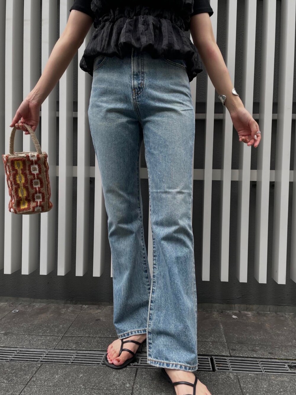 ブルー系のデニムパンツ、ブラック系のTシャツ/カットソー、ベージュ系のハンドバッグを着用したレディースの夏コーディネートの5枚目の写真