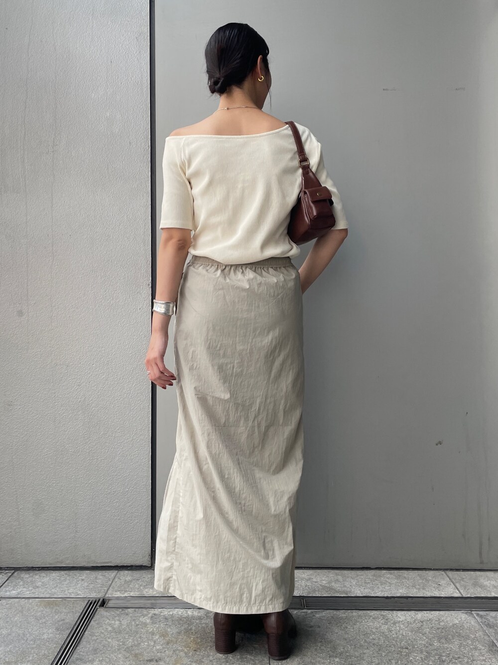 ベージュ系のスカート、ホワイト系のTシャツ/カットソー、ブラウン系のブーツを着用したレディースの夏コーディネートの3枚目の写真