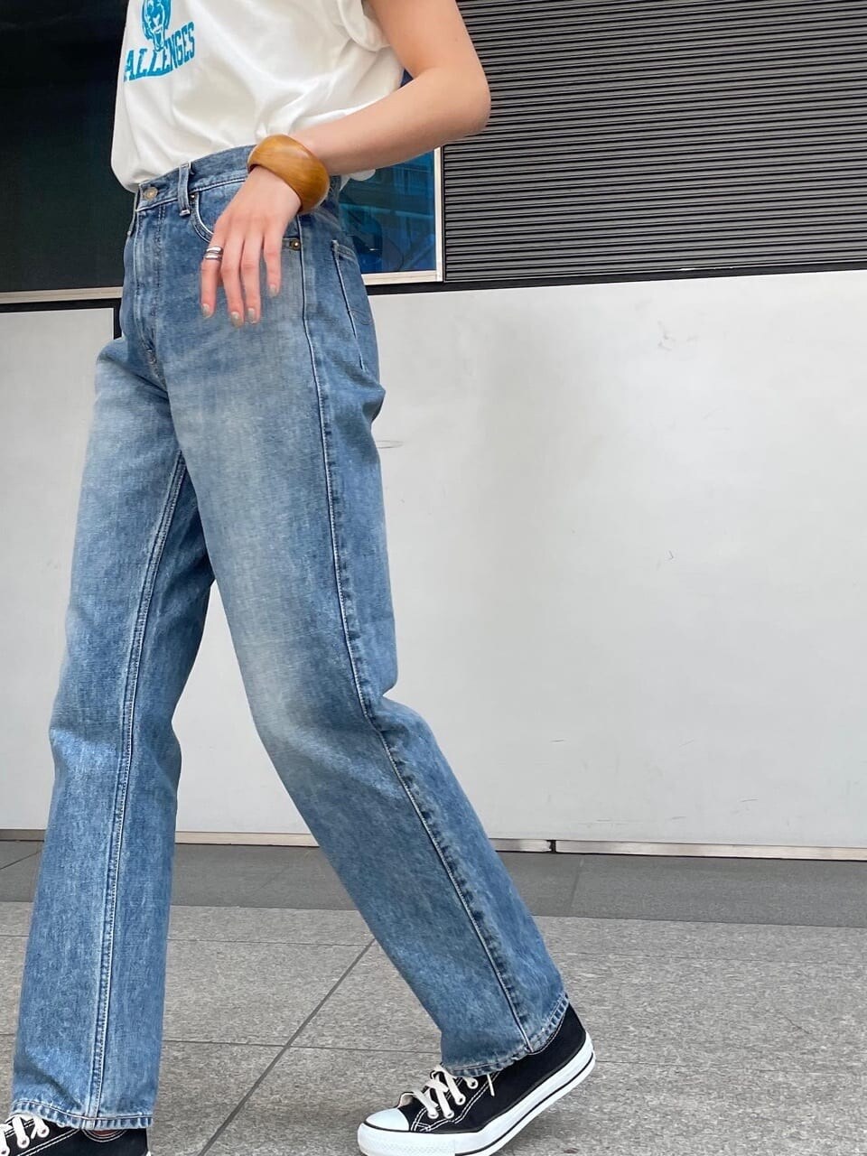 ホワイト系のTシャツ/カットソー、ブルー系のデニムパンツ、ブラウン系のブレスレットを着用したレディースの春コーディネートの3枚目の写真