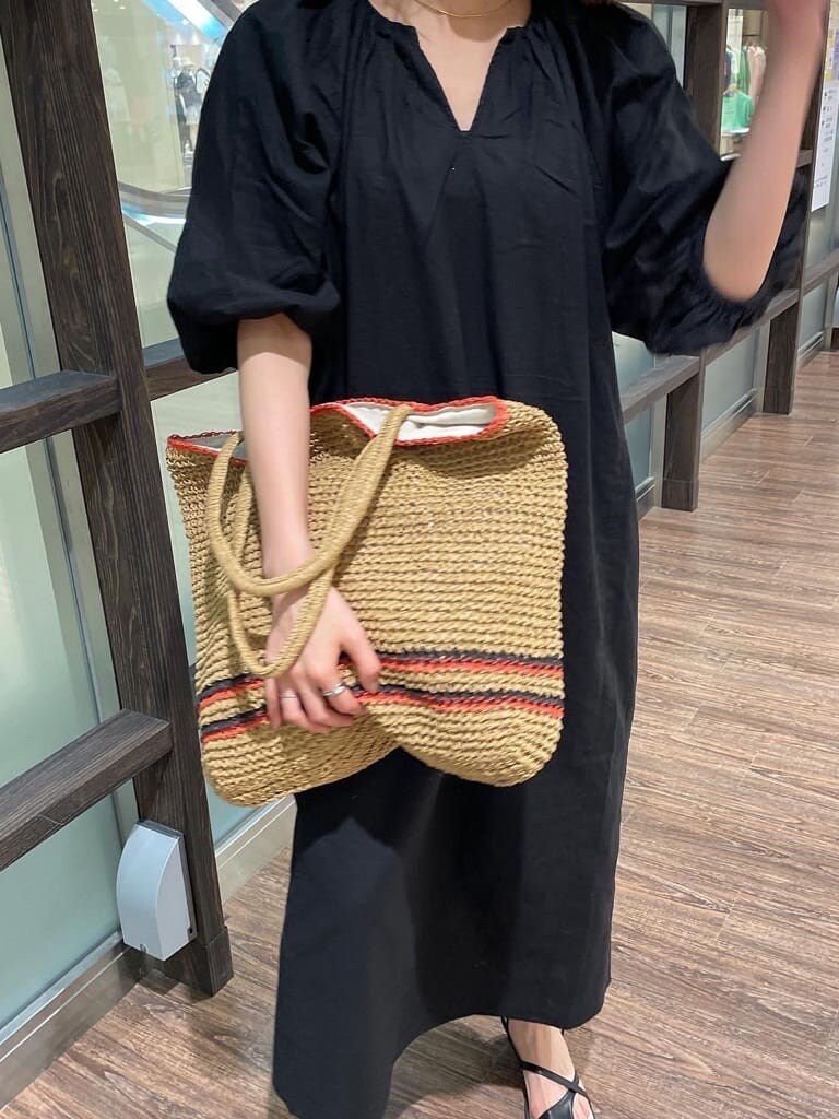 ブラック系のワンピース、ブラック系のサンダル、ベージュ系のトートバッグを着用したレディースの春コーディネートの3枚目の写真