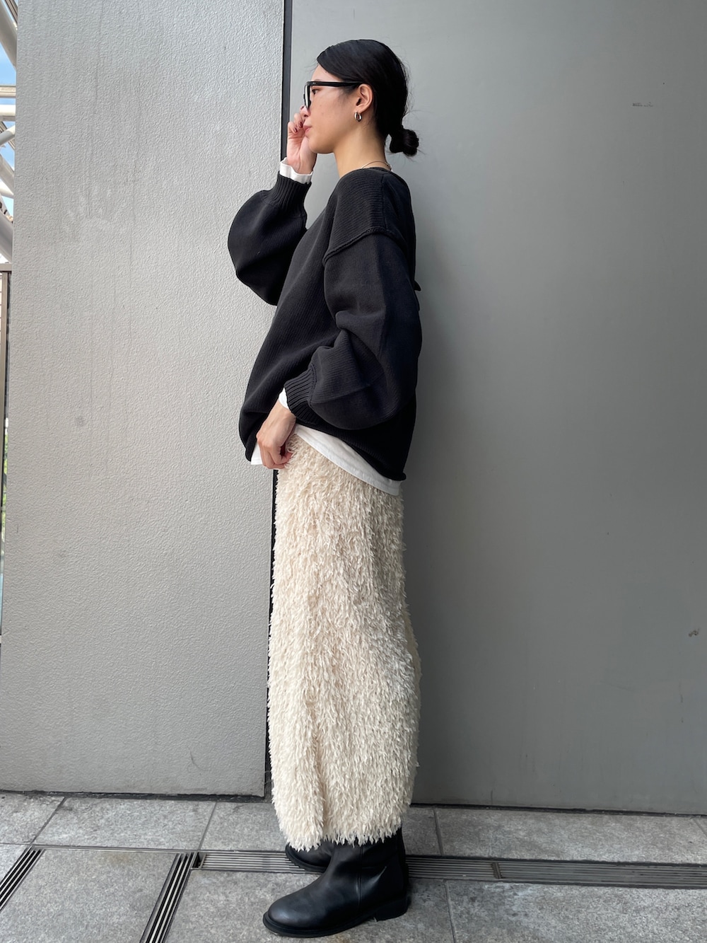 グレー系のニット/セーター、ホワイト系のTシャツ/カットソー、ホワイト系のスカートを着用したレディースの秋コーディネートの3枚目の写真