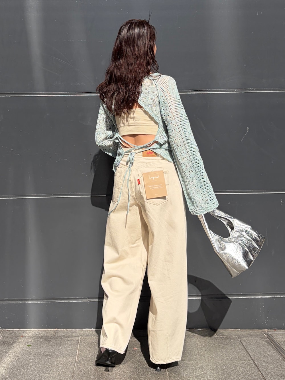 ブルー系のニット/セーター、ホワイト系のデニムパンツ、シルバー系のハンドバッグを着用したレディースの春コーディネートの2枚目の写真