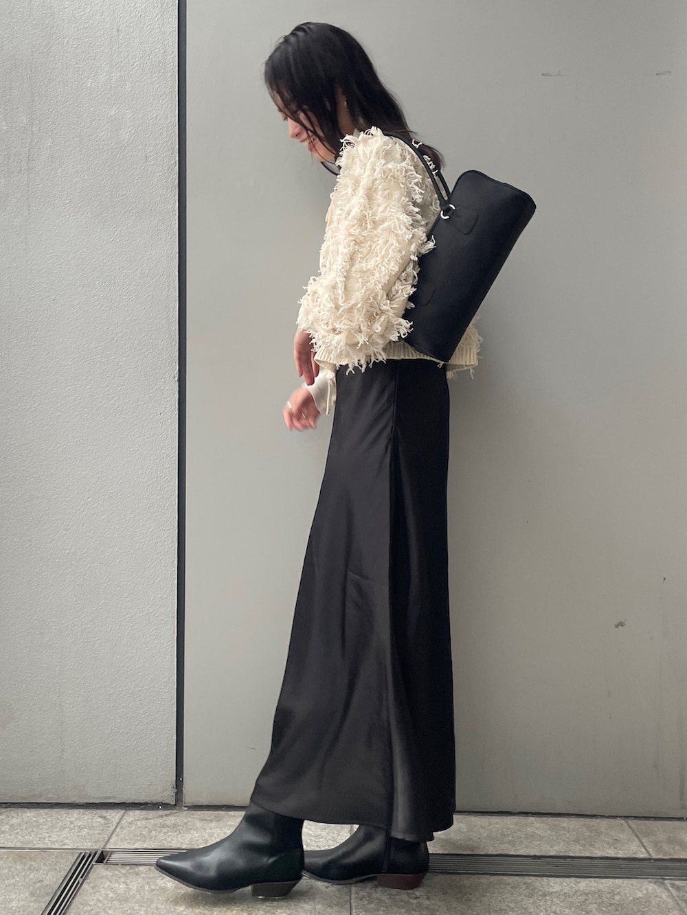 ホワイト系のニット/セーター、ブラック系のスカート、ブラック系のブーツを着用したレディースの秋コーディネートの2枚目の写真