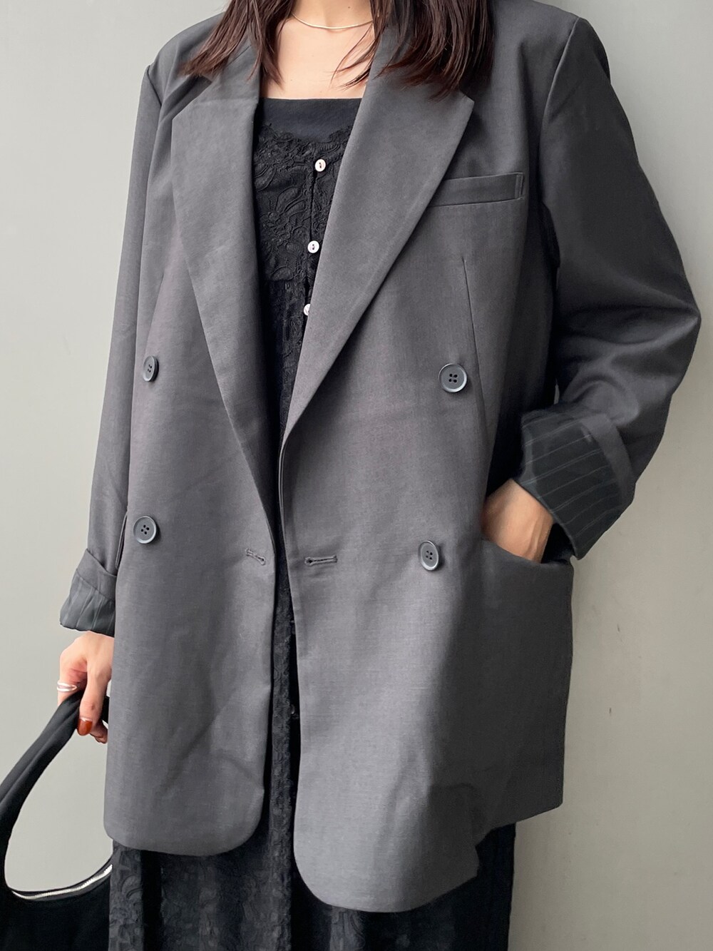 グレー系のテーラードジャケット、ブラック系のワンピース、ブルー系のデニムパンツを着用したレディースの秋コーディネートの4枚目の写真