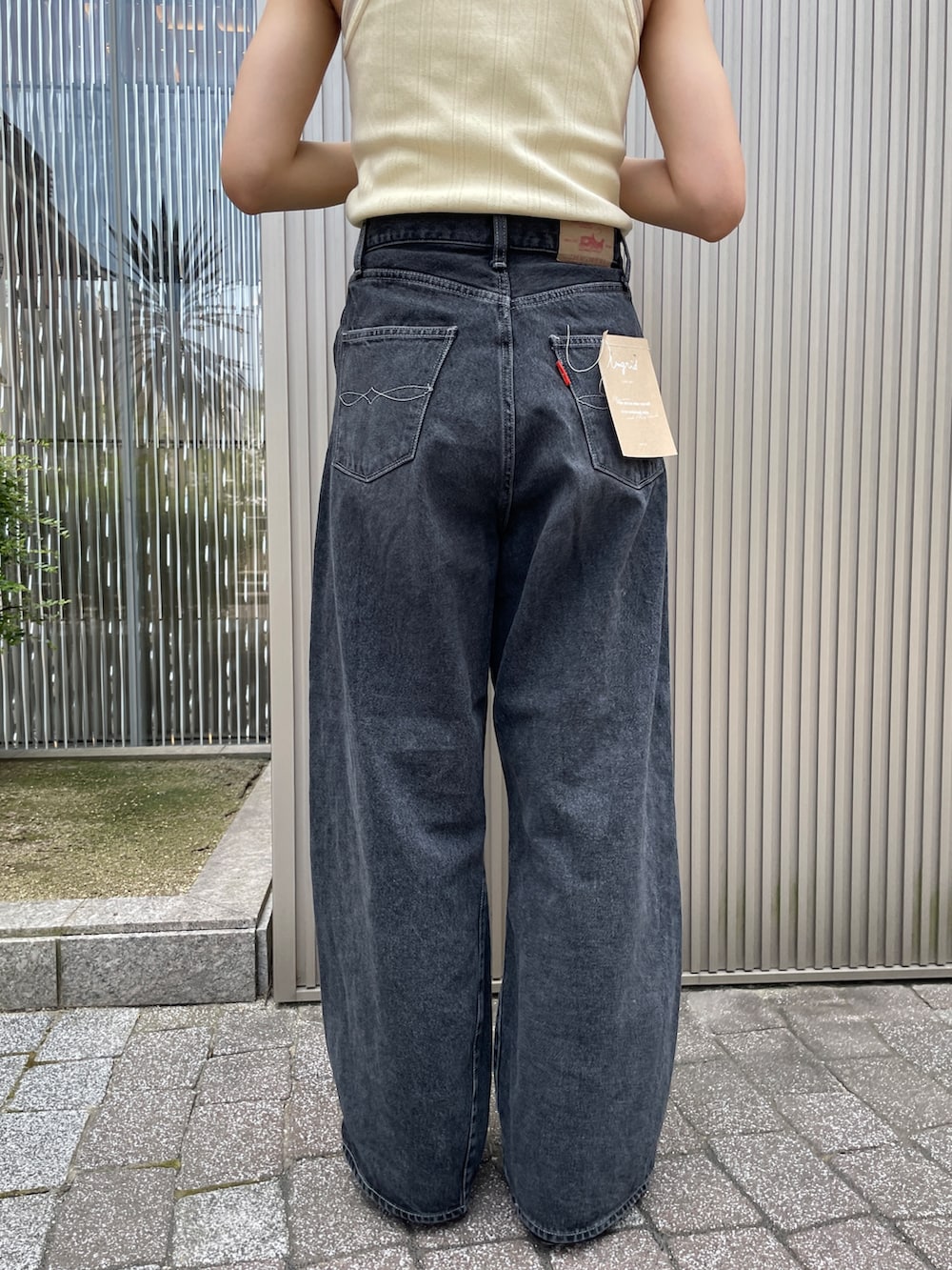 イエロー系のタンクトップ、ブラック系のデニムパンツ、ブラック系のサンダルを着用したレディースの夏コーディネートの4枚目の写真