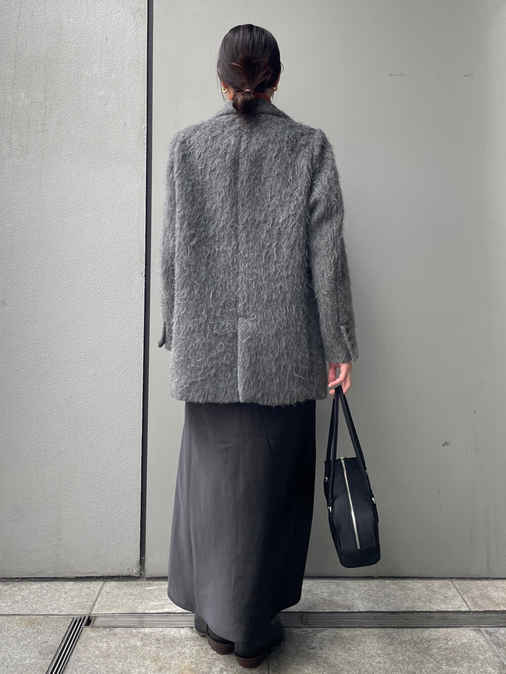 グレー系のテーラードジャケット、ブラック系のスカート、ブラック系のハンドバッグを着用したレディースの冬コーディネートの3枚目の写真