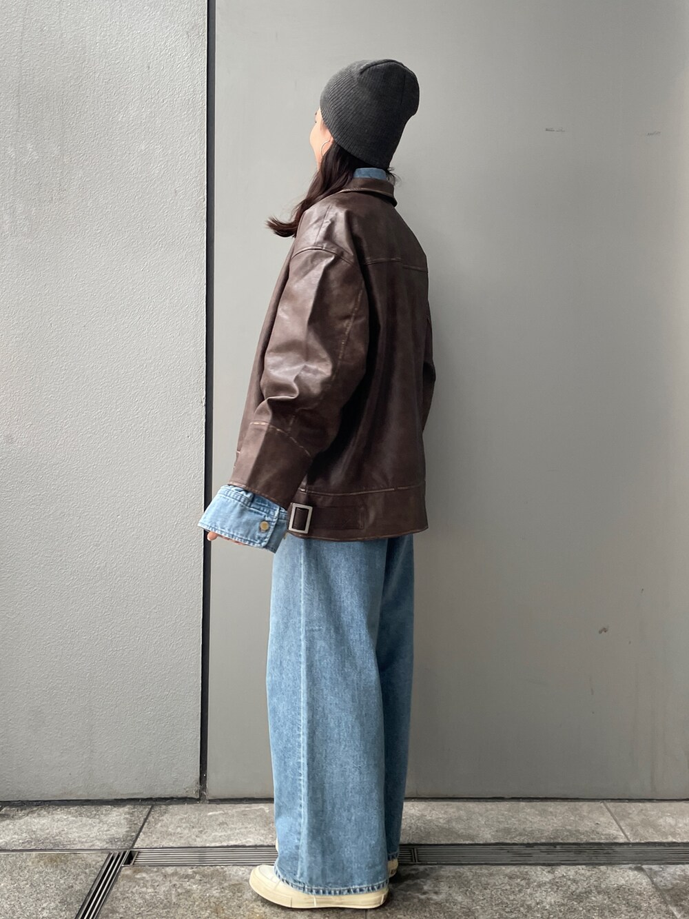 ブラウン系のブルゾン、ホワイト系のエコバッグ/サブバッグ、ブルー系のデニムパンツを着用したレディースの冬コーディネートの3枚目の写真