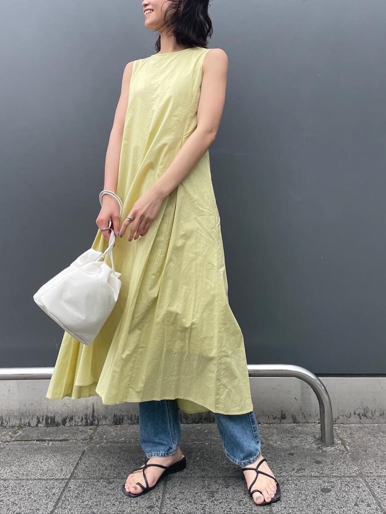 ホワイト系のハンドバッグ、ブルー系のデニムパンツ、グリーン系のワンピースを着用したレディースの春コーディネートの2枚目の写真