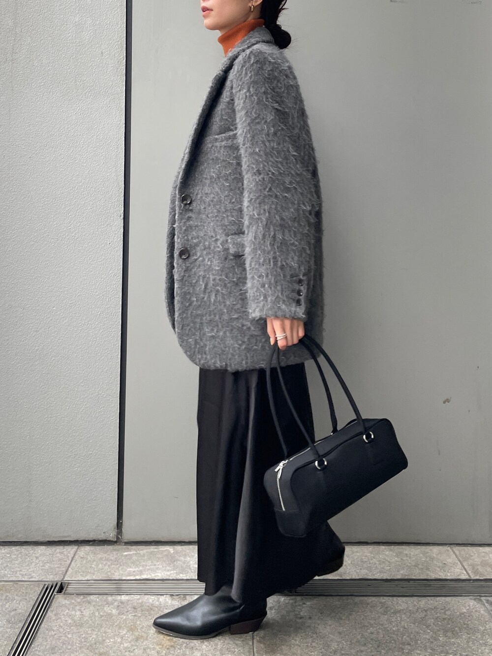 グレー系のテーラードジャケット、ブラック系のスカート、ブラック系のハンドバッグを着用したレディースの冬コーディネートの2枚目の写真